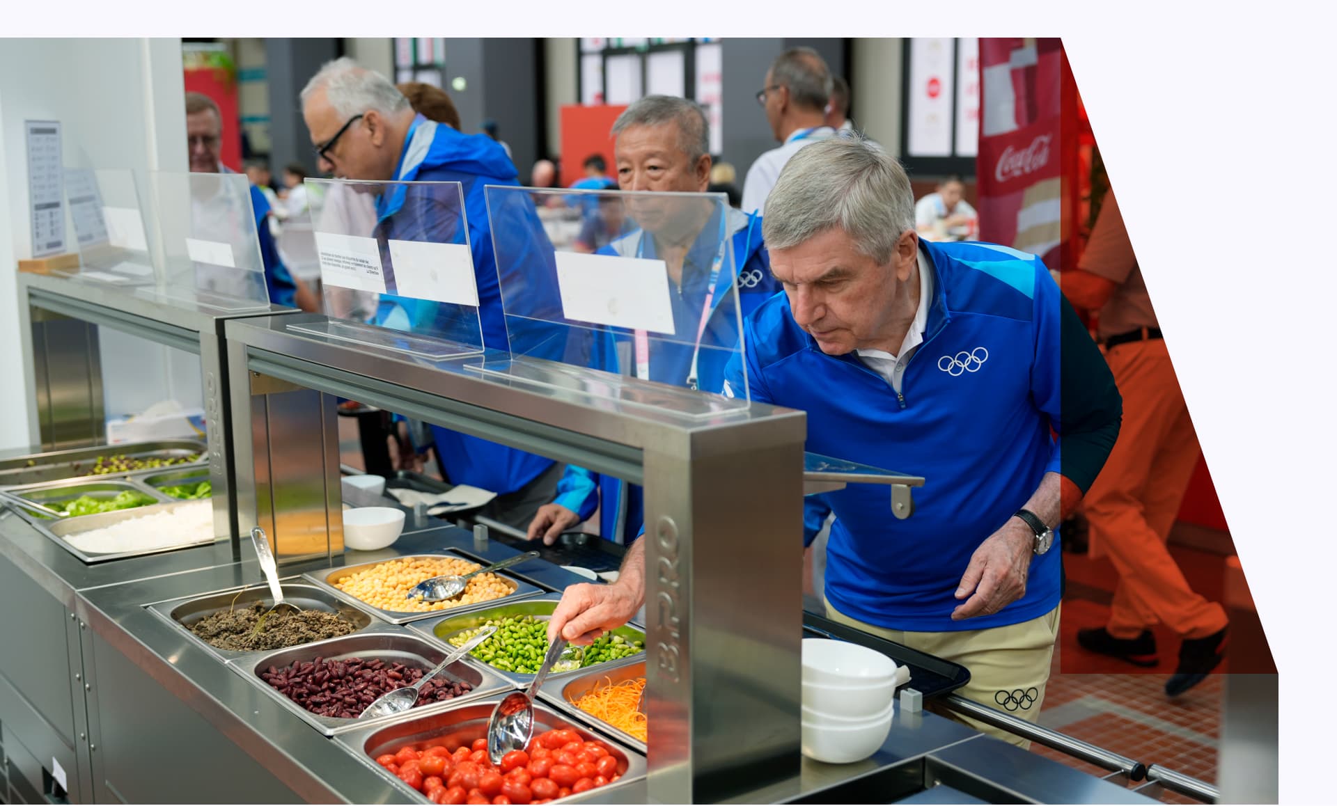 IOC staff trying food from a salad bar while touring the Olympic Village.