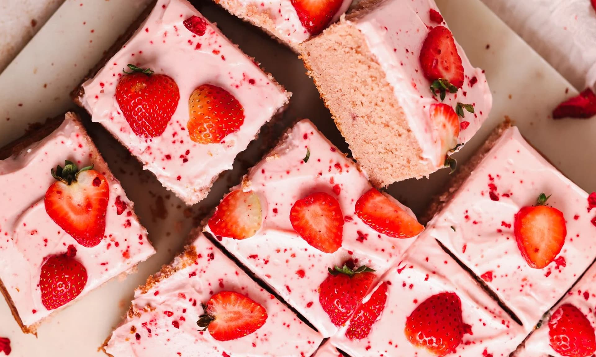 Pink short cake squares with pink frosting and strawberries on them